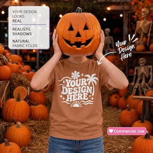 May include: A rust-colored t-shirt featuring a white graphic print with the text YOUR DESIGN HERE, a flower, a palm tree, and a sun. The shirt is displayed in a pumpkin patch setting with a carved jack-o'-lantern held up in front of the face.