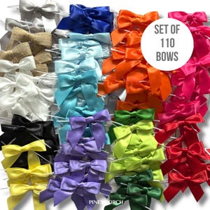 May include: A collection of 110 satin bows in various colors, including silver, burlap, white, blue, orange, pink, purple, green, yellow, and black. The bows are arranged in rows and columns, with the text "SET OF 110 BOWS" in a white circle.
