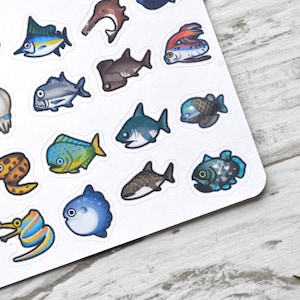 May include: A sheet of colourful stickers featuring various types of fish, including a shark, a pufferfish, a moray eel, and a swordfish. The stickers are on a white background.
