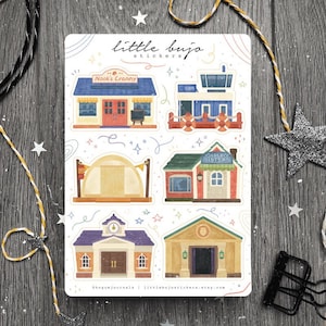 May include: A sheet of stickers featuring illustrations of buildings from the Animal Crossing video game. The stickers include Nook's Cranny, the airport, Able Sisters, the museum, and the town hall. The stickers are printed on white paper with a light brown background.