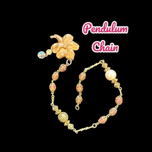May include: A gold-coloured pendulum chain featuring a floral top and a sequence of pink and gold beads. The chain is finished with a pearl, and the text "Pendulum Chain" is in pink.