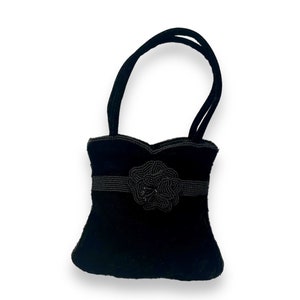 May include: A small black velvet handbag with a beaded flower embellishment and two top handles.