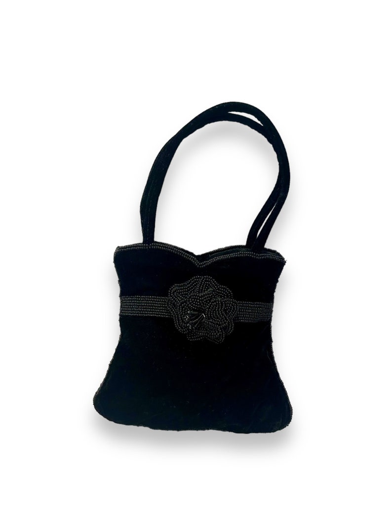 May include: A small black velvet handbag with a beaded flower embellishment and two top handles.