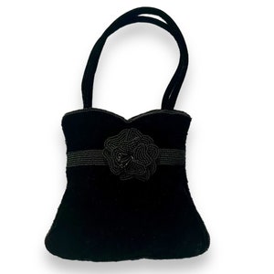 May include: A small black velvet handbag with a beaded flower embellishment.