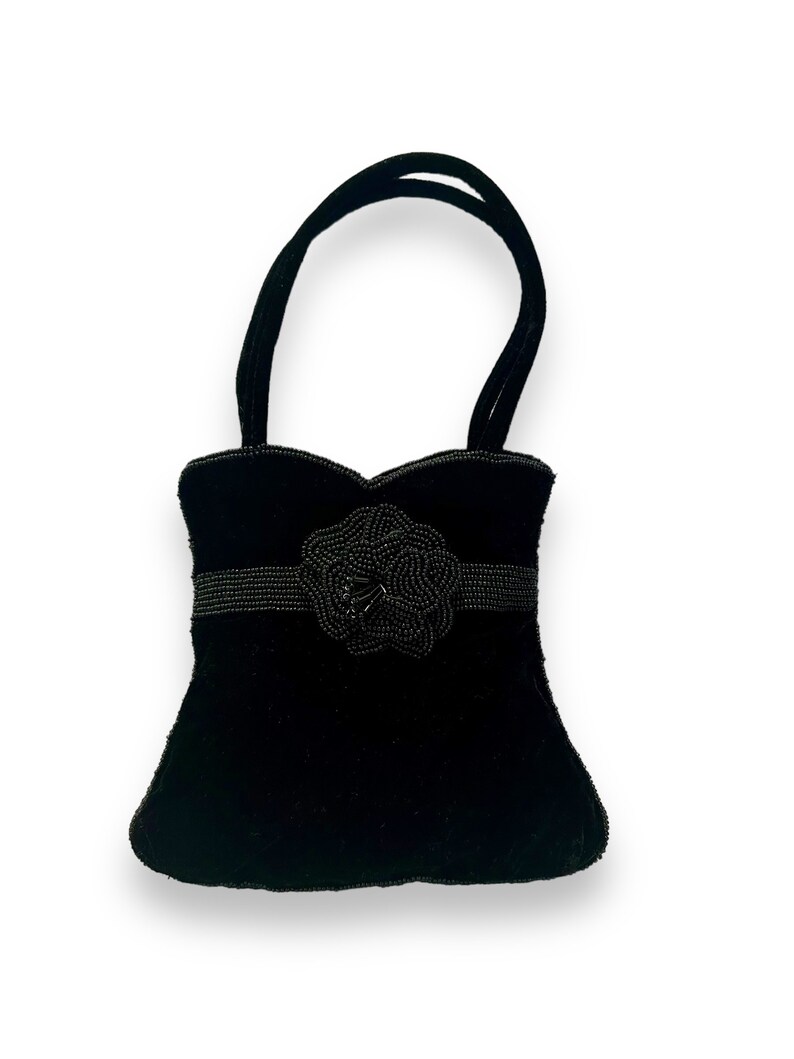 May include: A small black velvet handbag with a beaded flower embellishment.