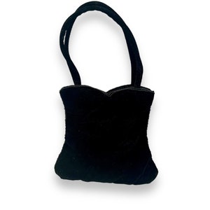 May include: A small black velvet handbag with a heart-shaped design and a single top handle.