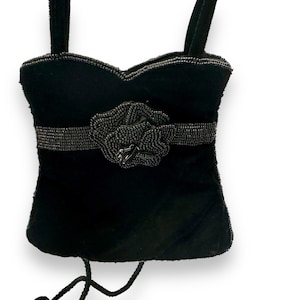 May include: A black velvet evening bag with a beaded flower accent and a chain strap.