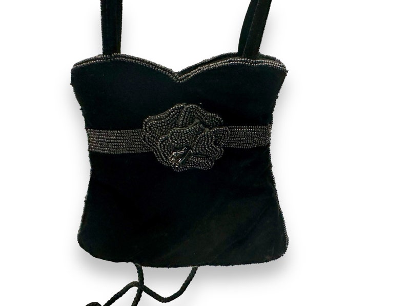 May include: A black velvet evening bag with a beaded flower accent and a chain strap.