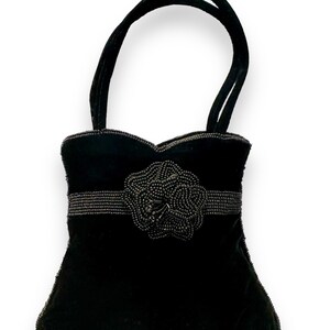 May include: A black velvet handbag with a beaded flower design and a top handle.