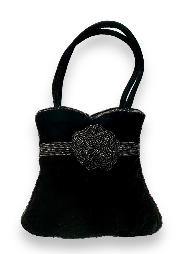 May include: A black velvet handbag with a beaded flower design and a top handle.