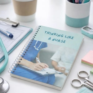May include: A spiral-bound notebook with the text "THINKING LIKE A NURSE" in light blue. The notebook features an image of a nurse writing on a clipboard. Other items include a stethoscope, pens, and a coffee cup.