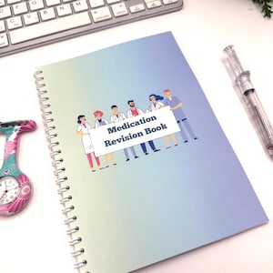 May include: A spiral-bound notebook with a blue and green gradient cover. The cover displays an illustration of medical staff holding a banner with the text "Medication Revision Book". A keyboard, pen, and a nurse's watch are also visible.
