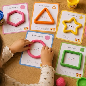 May include: A set of educational activity cards featuring shapes including a hexagon, triangle, star, circle, and square. Each card displays the text 'I can make a' followed by the shape name and a smiling face illustration, with colorful modeling clay.