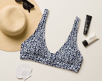 May include: A navy blue bikini top with a white abstract pattern. The top has a scoop neck and adjustable straps.