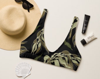 May include: Black bikini top with a green and white leafy print. The top has a scoop neck and adjustable straps.