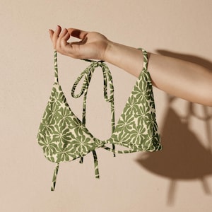 May include: A green and white floral print bikini top with adjustable straps.