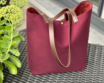 Plum-colored tote bag, floral interior, zippered pocket, brown leather handles!