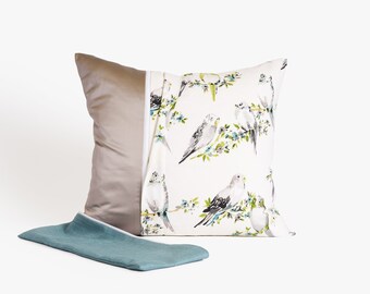 May include: A white pillow cover with a zipper closure and a beige fabric backing. The front of the pillow cover features a repeating pattern of watercolor-style birds and green leaves.
