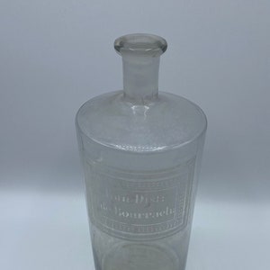 May include: A clear glass bottle with a textured surface and a label that reads "Eau Distillee de Bourrache".