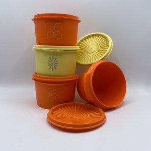 Könnte beinhalten: Ein Satz von vier orangefarbenen und gelben Plastikbehältern mit Deckeln. Die Behälter haben ein Blumen- und Sternmuster.