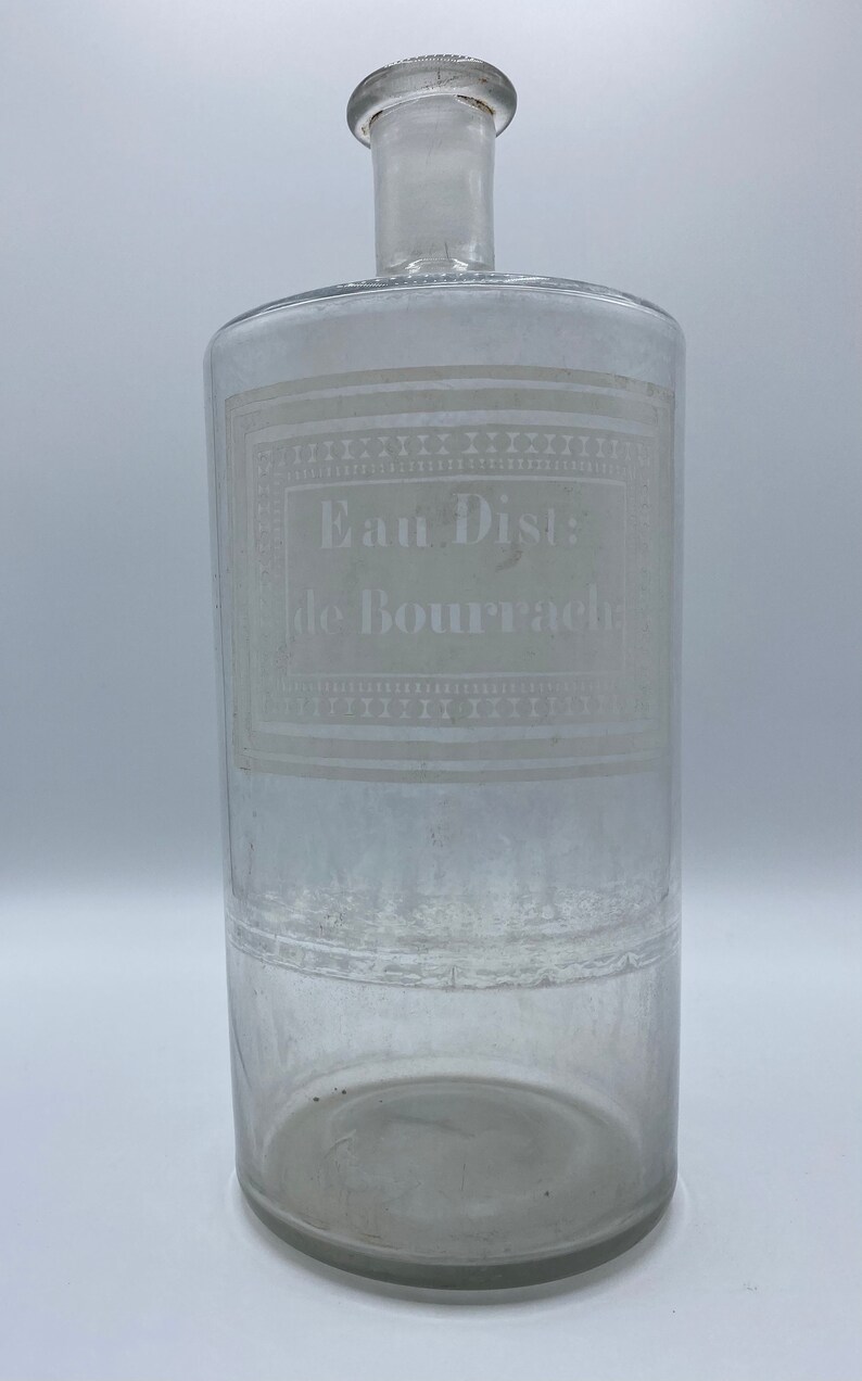 May include: A clear glass bottle with a white label that reads "Eau Dist: de Bourrach".