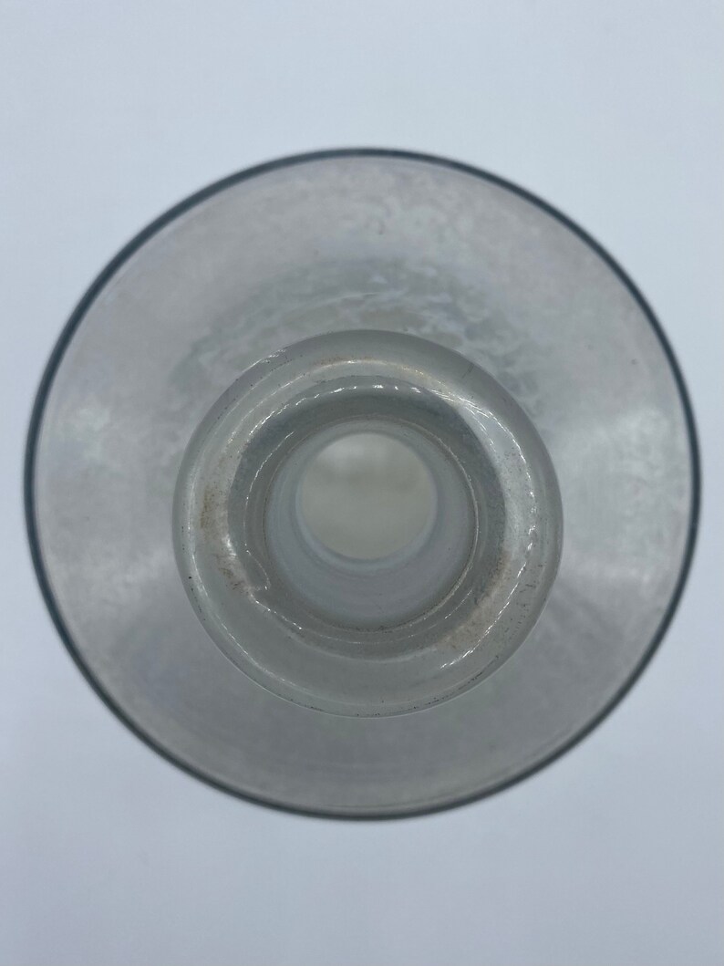 May include: A clear glass bottle with a wide mouth and a smooth, rounded bottom. The bottle is empty and has a slight frosted appearance.