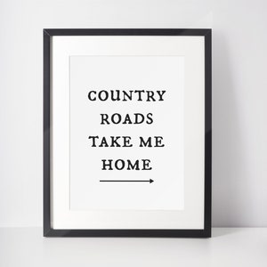 May include: Black framed print with the text "COUNTRY ROADS TAKE ME HOME" and an arrow pointing to the right.