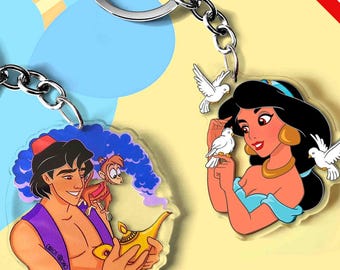 May include: Two acrylic keychains featuring cartoon characters. One keychain shows a man with a monkey and a golden lamp. The other keychain shows a woman with three white doves. Both keychains have silver metal rings and chains attached.