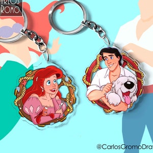 May include: Two round acrylic keychains featuring characters from the Disney film The Little Mermaid. The first keychain shows Ariel, a red-haired mermaid, wearing a pink dress and holding a fork. The second keychain shows Prince Eric, a human prince, holding a white dog. Both keychains have a red rope design around the edge.