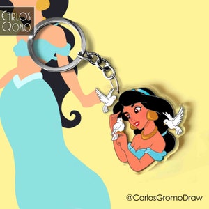 K&ouml;nnte beinhalten: Ein durchsichtiger Acryl-Schl&uuml;sselanh&auml;nger mit einer Cartoon-Illustration von Prinzessin Jasmin aus Disneys Aladdin. Jasmin tr&auml;gt ein blaues und goldenes Outfit und h&auml;lt zwei wei&szlig;e Tauben. Der Schl&uuml;sselanh&auml;nger ist an einem silbernen Schl&uuml;sselring befestigt.