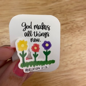 May include: White sticker with black text that reads "God makes all things new."  Revelation 21:5 is printed below the text. Three colorful flowers are illustrated below the text.