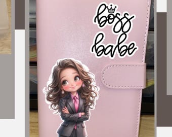 May include: A pink planner with a sticker that says "boss babe" and a cartoon image of a woman in a suit. A clear pouch with a pink label and a cartoon image of a woman. A budget sheet.