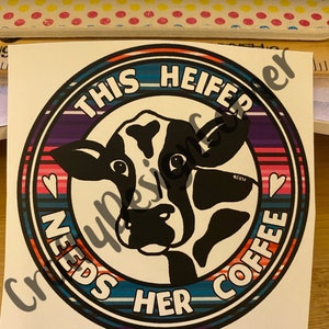 May include: A round sticker with a colorful striped border and a cow's head in the center. The text on the sticker reads "This Heifer Needs Her Coffee".