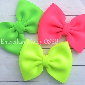 May include: Three neon-colored hair bows. One bow is bright green, one is bright pink, and one is a lighter shade of green.