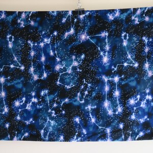 May include: A dark blue fabric with a white constellation pattern. The fabric features a repeating pattern of constellations with white stars and lines.