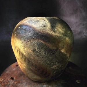 May include: A spherical ceramic vase with a textured surface. The vase has a marbled effect with brown, black, and gold tones. The opening is a simple, flat rim. A unique decorative piece. Measurements are in centimetres.