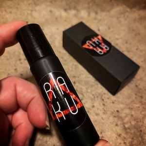 May include: A black roller bottle with a red and white triangle logo that says "RAKU" inside the triangle. The bottle is being held by a hand.