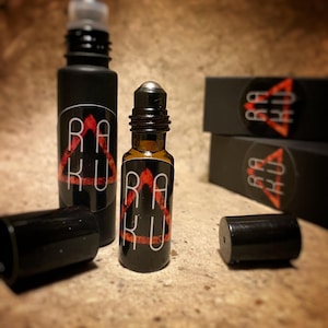 May include: Two black roller bottles with a red and black logo that says "RAKU" on the label. The bottles are on a brown surface.