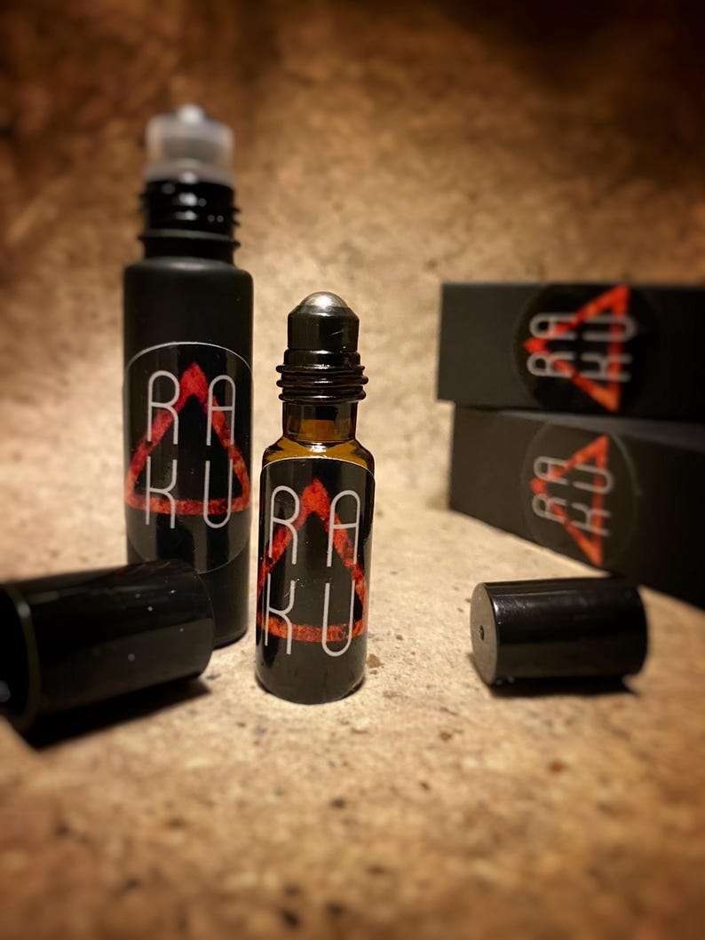 May include: Two black roller bottles with a red and black logo that says "RAKU" on the label. The bottles are on a brown surface.