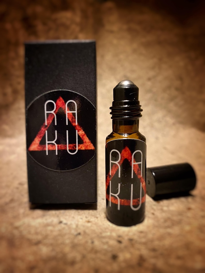 May include: A black and red roll-on bottle with the word "RAKU" in a triangle design. The bottle is next to a black box with the same design.