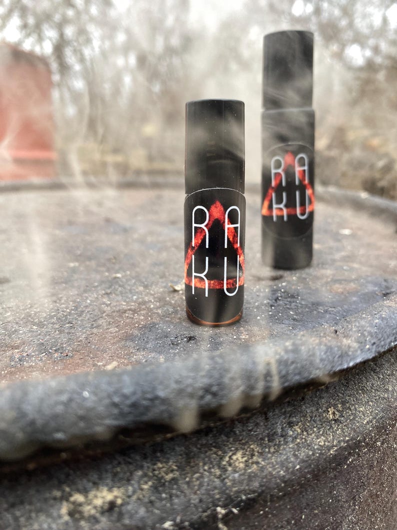 May include: Two small black bottles with red and white labels that say "RAKU" in a triangular design. The bottles are sitting on a rusty surface.