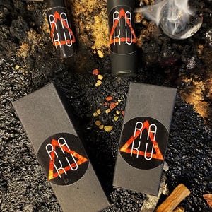 May include: Three black boxes with a red triangle logo that says "RAKU" on them. Two of the boxes are small and contain roll-on bottles. The third box is larger and is empty.