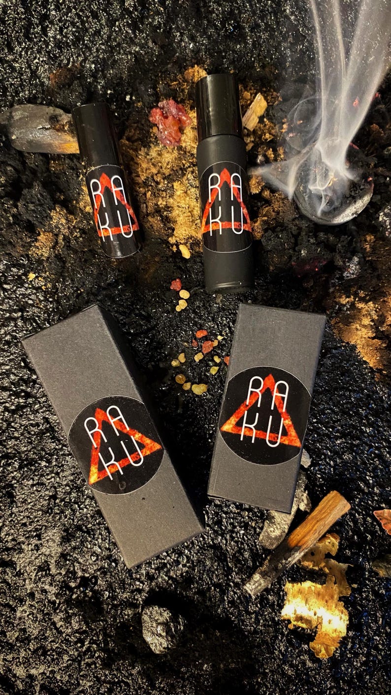 May include: Three black boxes with a red triangle logo that says "RAKU" on them. Two of the boxes are small and contain roll-on bottles. The third box is larger and is empty.