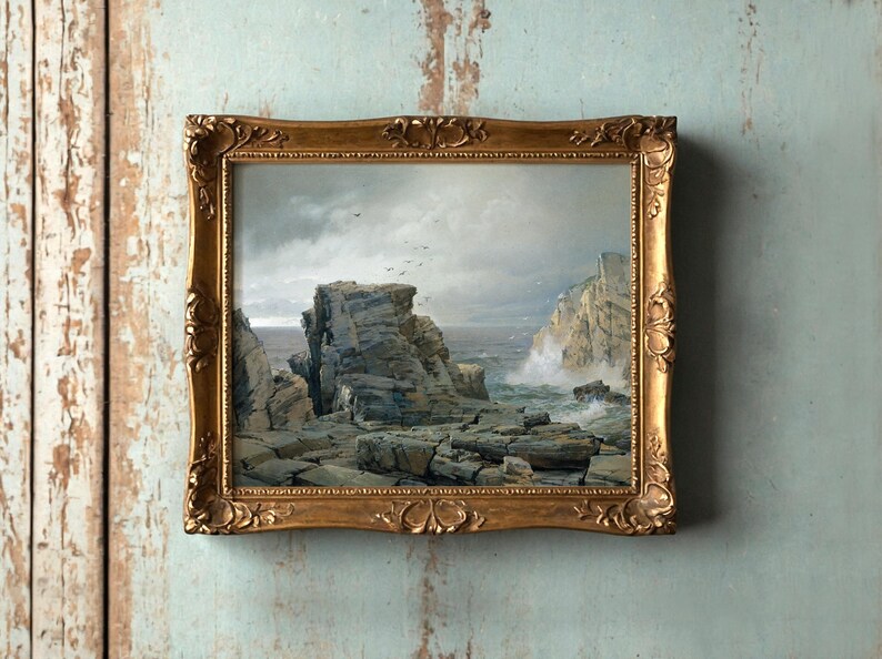 A painting in an ornate gold frame shows a rugged coastal scene. Cliffs rise against a cloudy sky; waves crash on rocks, evoking a dramatic, serene mood.