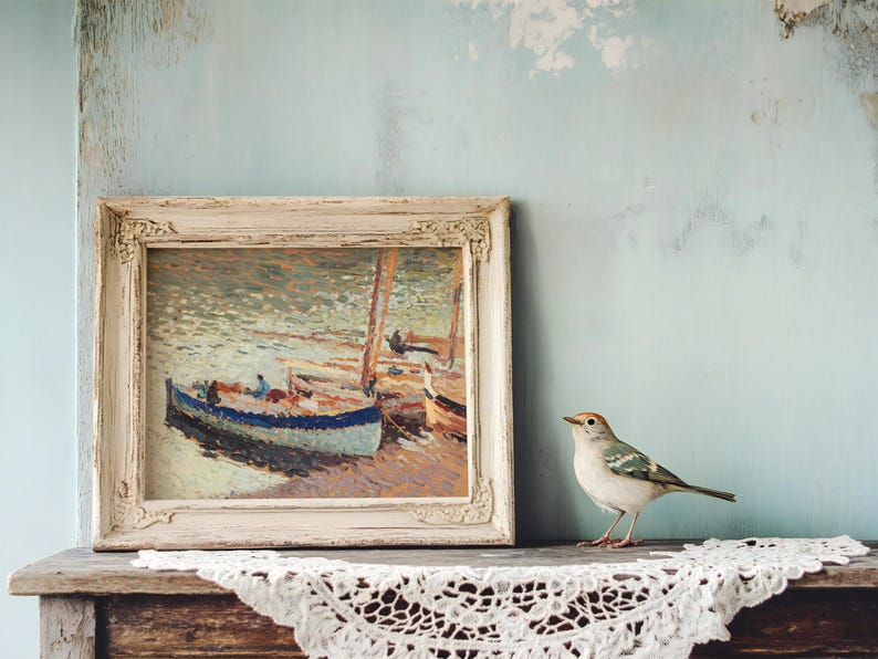 A framed painting of boats on water rests on a rustic wooden shelf with crochet lace. A small bird is perched beside it, creating a serene and artistic scene.