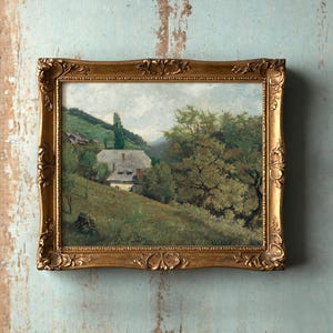 Framed landscape painting on a textured wall depicts a serene countryside with a cottage, lush green hills, and a large tree, evoking tranquility.