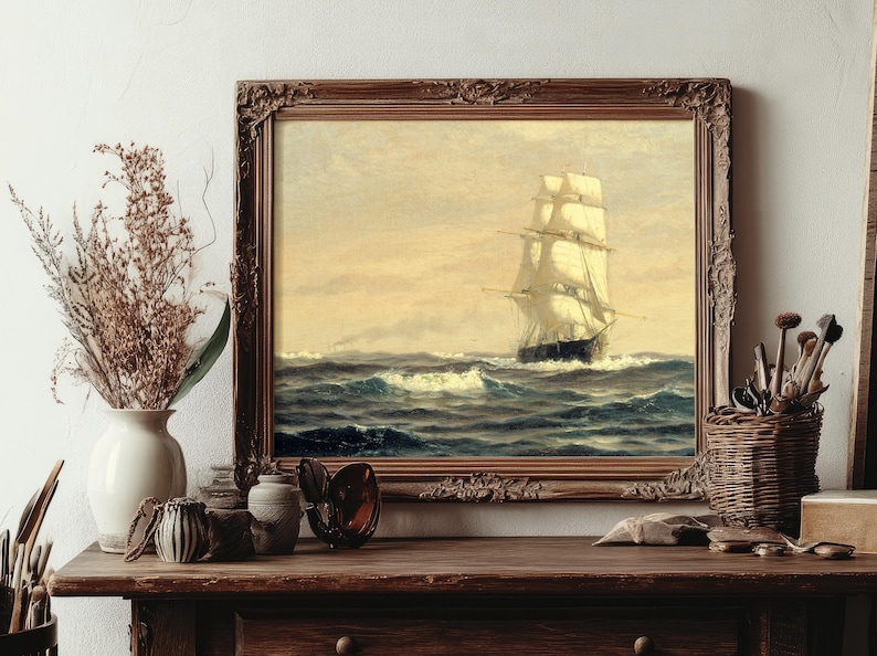 The scene is a cozy, vintage-inspired still life with a framed painting of a sailing ship, dried branches and a green leaf in a vase, dried flowers and brushes in a basket, and various decorative items like shells, glasses, and a box on a wooden surface.