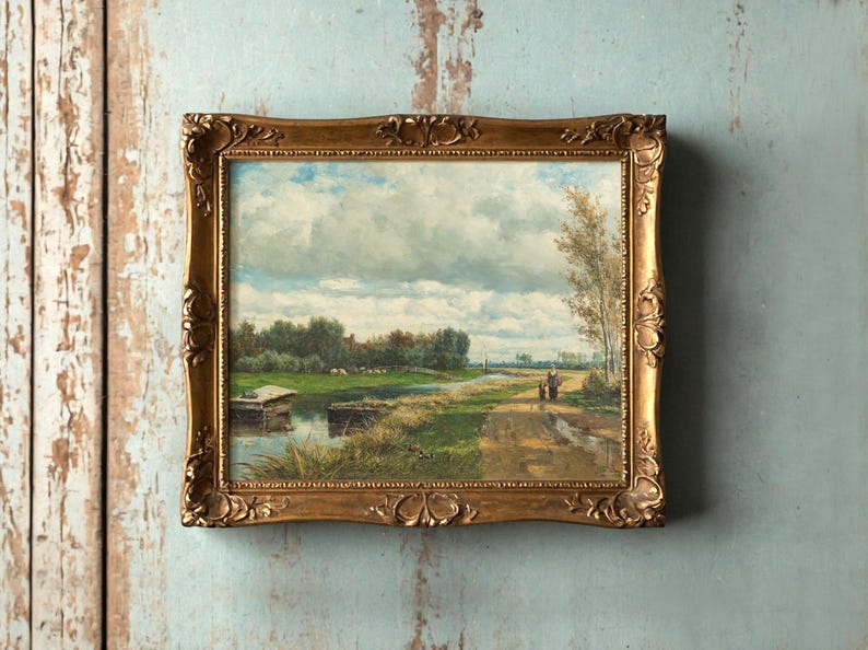 Framed landscape painting on a textured wall, depicting a serene countryside with a waterway, lush greenery, and cloudy sky, evokes tranquility.