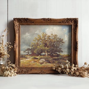 A rustic wooden frame holds a landscape painting of a tree under a cloudy sky. Dried flowers in a jar and scattered on a white surface surround it, creating a calm, nostalgic atmosphere.