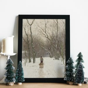 Framed winter landscape painting features a lone figure on a snowy path lined with bare trees. Candle and miniature evergreen trees add a festive touch.